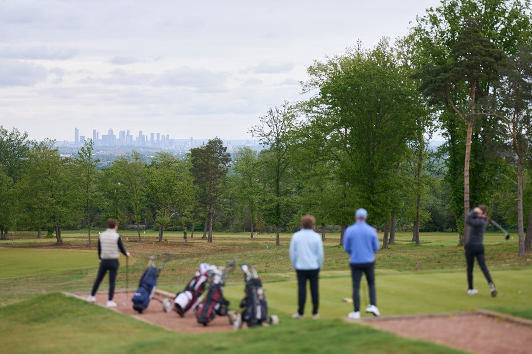 Golfers playing on a course with a distant city skyline.