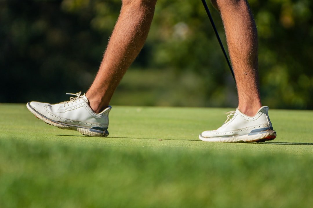 Close-up of white golf shoes walking across a green.