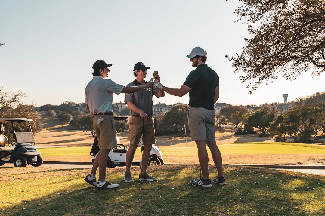 Three friends talking together on a golf course at golden hour.