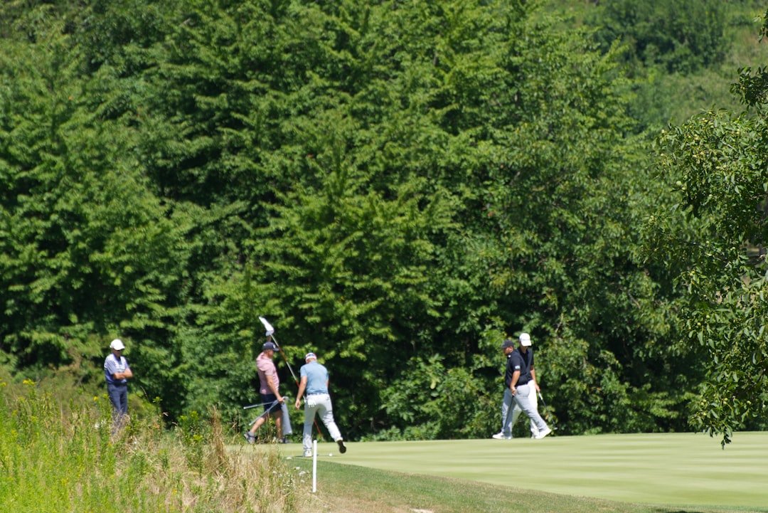Golfers playing on a green course with trees in background